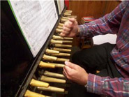 Le carillonneur joue des poings sur son clavier et des pieds sur son pédalier